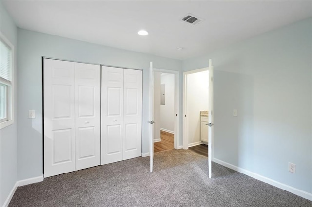 unfurnished bedroom featuring carpet flooring, baseboards, a closet, electric panel, and recessed lighting
