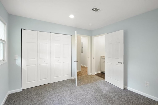 unfurnished bedroom with carpet floors, baseboards, a closet, recessed lighting, and electric panel