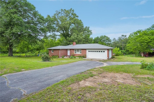 single story home with a chimney, asphalt driveway, a front yard, an attached garage, and view of scattered trees