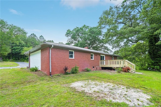 rear view of property with a wooden deck, a lawn, brick siding, and a garage