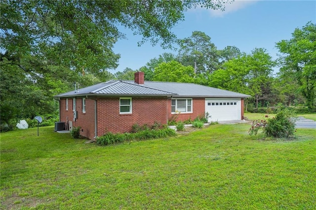 view of property exterior with a chimney, cooling unit, an attached garage, a yard, and brick siding