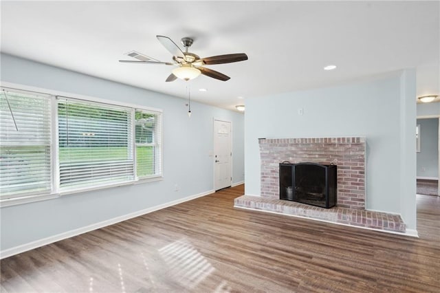unfurnished living room featuring wood finished floors, a ceiling fan, baseboards, a brick fireplace, and recessed lighting