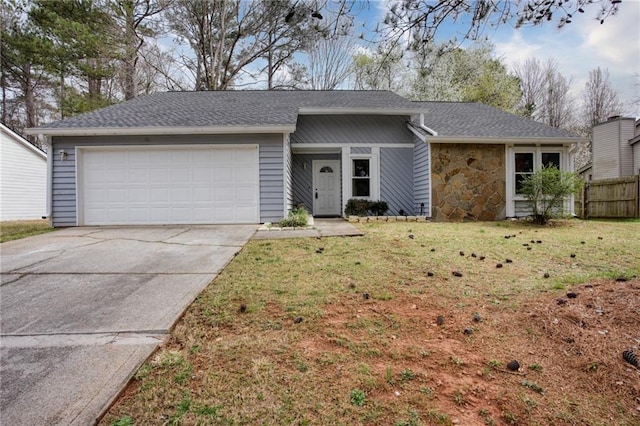 view of front of house with stone siding, fence, concrete driveway, a front yard, and a garage