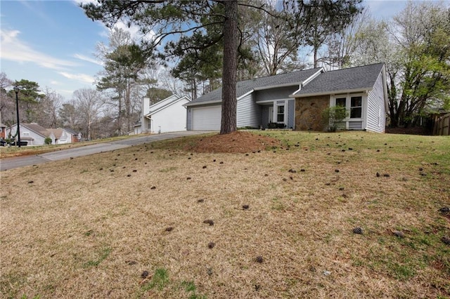 single story home with a front lawn, an attached garage, roof with shingles, and driveway