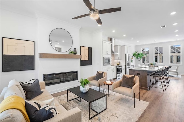 4933 Sudbrook Way Unit 230, Peachtree Corners, GA 30092 - living room with light wood-style flooring, a ceiling fan, crown molding, recessed lighting, and a glass covered fireplace