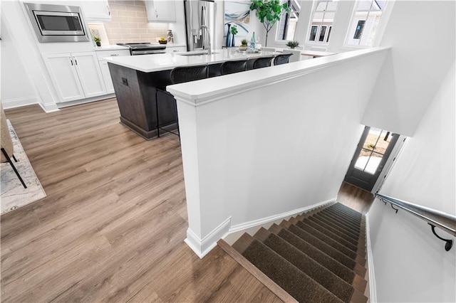 4933 Sudbrook Way Unit 230, Peachtree Corners, GA 30092 - kitchen with stainless steel appliances, a sink, a kitchen island with sink, light countertops, and light wood finished floors