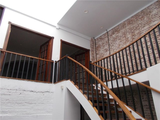 stairs with a towering ceiling and brick wall