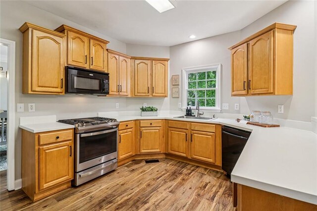 1006 Amberton Ln, Powder Springs, GA 30127 - kitchen with black appliances, wood finished floors, a sink, recessed lighting, and light countertops