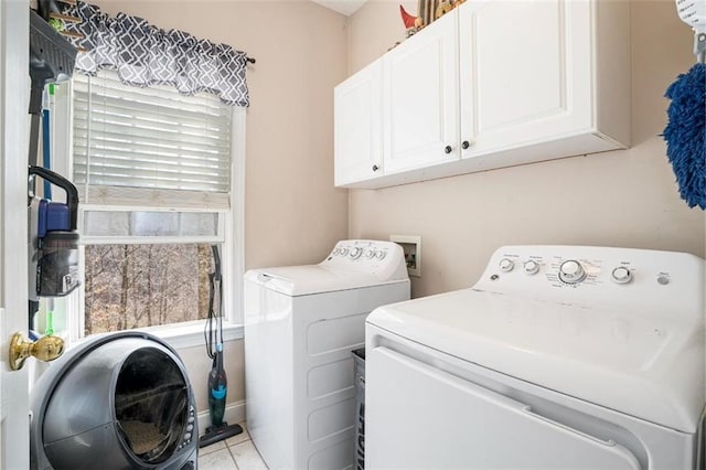 clothes washing area with cabinets, light tile patterned flooring, and washing machine and clothes dryer