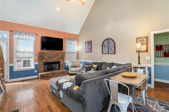 living room with high vaulted ceiling, a fireplace, and light hardwood / wood-style floors