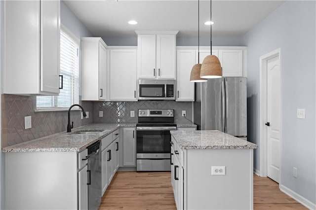 kitchen featuring light wood-type flooring, a sink, a kitchen island, white cabinetry, and appliances with stainless steel finishes