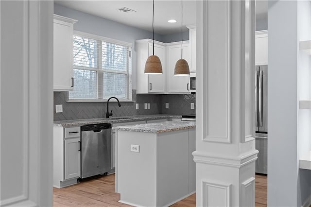 kitchen with tasteful backsplash, light wood-style flooring, appliances with stainless steel finishes, and white cabinets