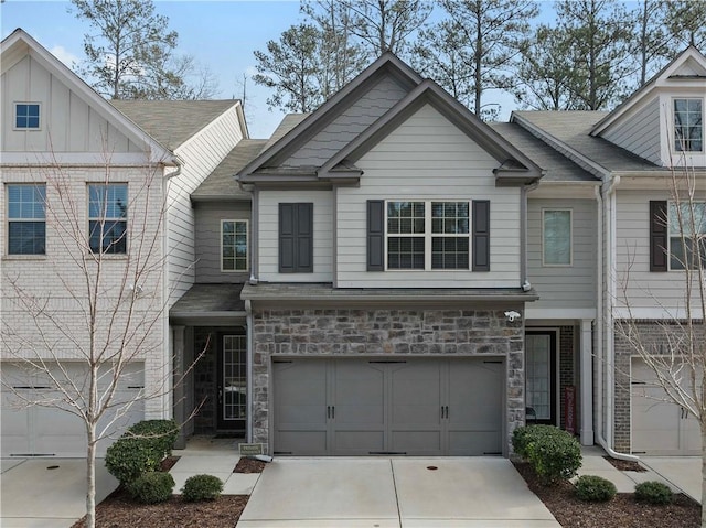 view of front facade with stone siding, driveway, an attached garage, and board and batten siding