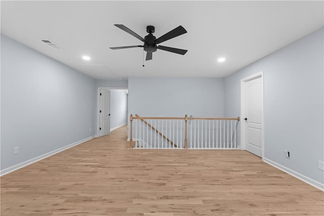 spare room with baseboards, recessed lighting, attic access, and light wood-style floors