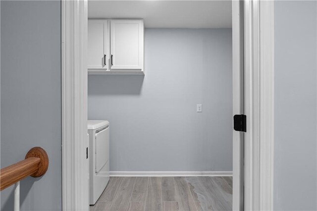 laundry area featuring washing machine and dryer, cabinet space, light wood-style flooring, and baseboards