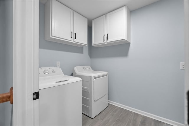 clothes washing area with light wood-style flooring, cabinet space, independent washer and dryer, and baseboards