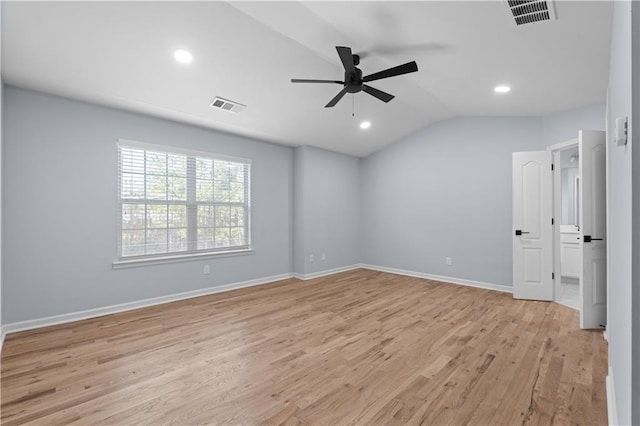 spare room with vaulted ceiling, baseboards, visible vents, and light wood-type flooring