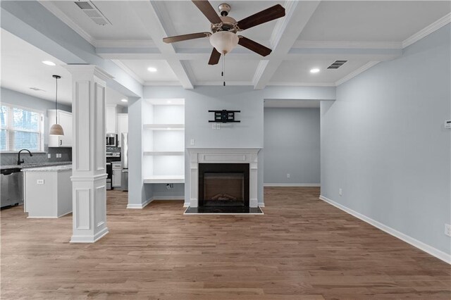 unfurnished living room featuring visible vents, coffered ceiling, a fireplace, light wood finished floors, and decorative columns