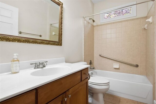 full bathroom featuring tile patterned flooring, vanity, tiled shower / bath combo, and toilet