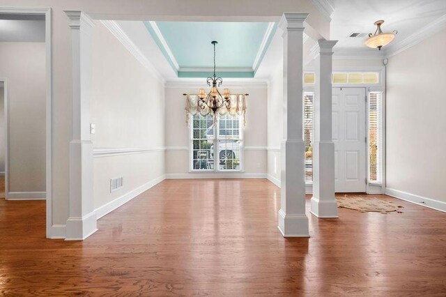 entrance foyer featuring a tray ceiling, crown molding, wood-type flooring, and an inviting chandelier