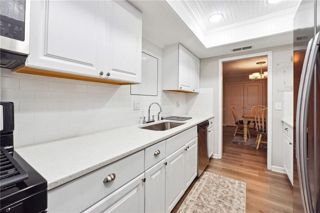 6851 Roswell Rd Unit E1, Atlanta, GA 30328 - kitchen with visible vents, crown molding, a sink, a raised ceiling, and stainless steel appliances