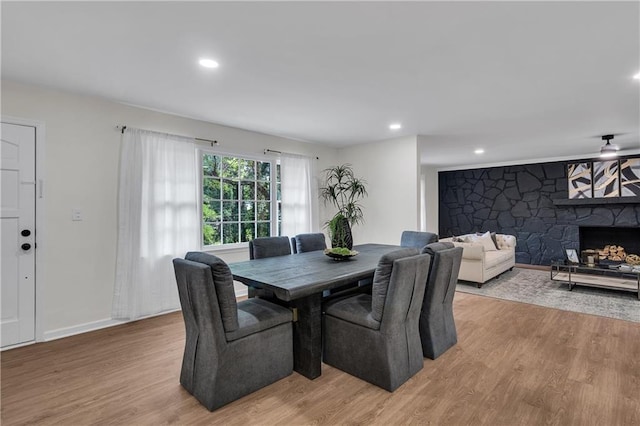 dining room with a stone fireplace and light wood-type flooring