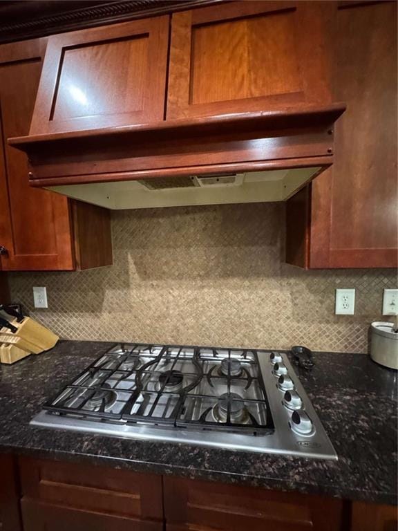 kitchen featuring extractor fan, stainless steel gas cooktop, and dark stone counters