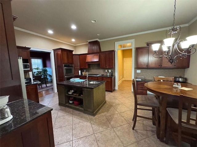 kitchen featuring tasteful backsplash, a chandelier, a kitchen island with sink, and hanging light fixtures