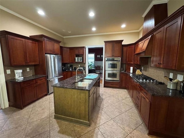 kitchen with sink, dark stone counters, custom range hood, stainless steel appliances, and a kitchen island with sink