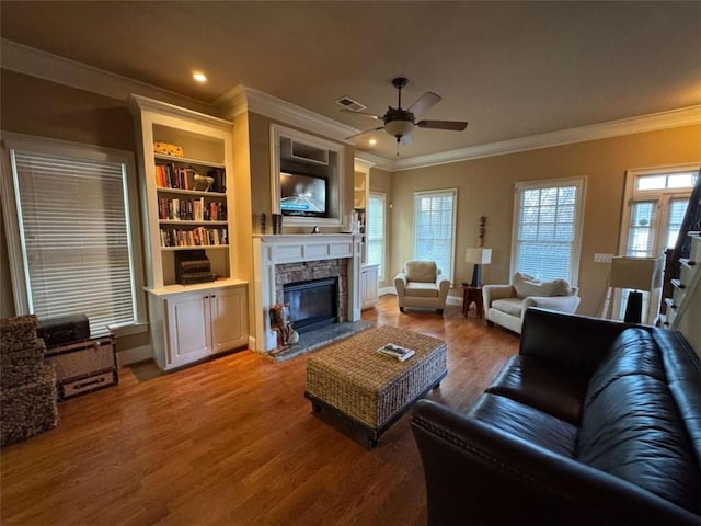 living room featuring hardwood / wood-style flooring, crown molding, ceiling fan, and a fireplace