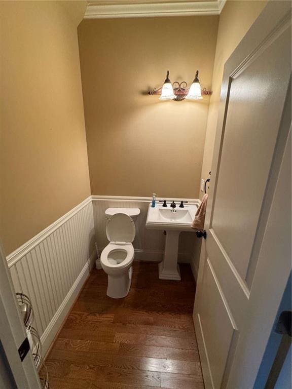 bathroom with hardwood / wood-style flooring, crown molding, and toilet