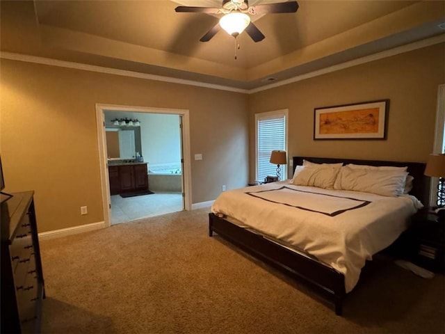 bedroom with ensuite bathroom, light colored carpet, ceiling fan, and a tray ceiling