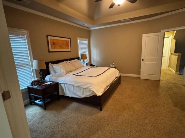 carpeted bedroom with multiple windows, ornamental molding, ceiling fan, and a tray ceiling