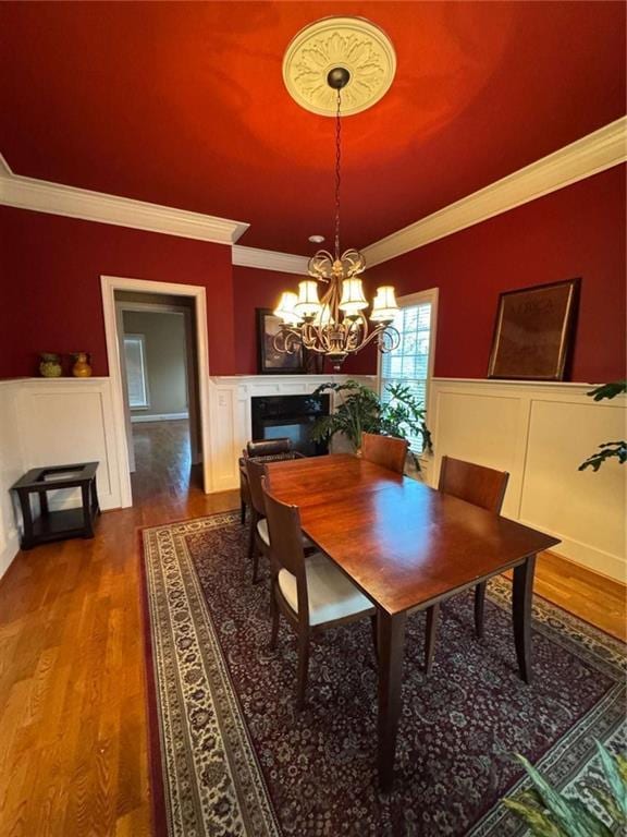 dining area with ornamental molding, wood-type flooring, and a chandelier