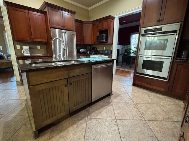 kitchen with sink, ornamental molding, appliances with stainless steel finishes, an island with sink, and decorative backsplash