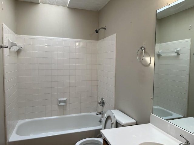 full bathroom featuring tiled shower / bath, vanity, and toilet