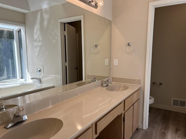 bathroom with wood-type flooring, toilet, a bathing tub, and vanity