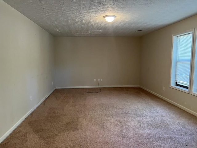 unfurnished room with a healthy amount of sunlight, carpet flooring, and a textured ceiling