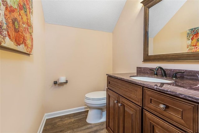 324 Kibbee Rd, Mcdonough, GA 30252 - half bath featuring vaulted ceiling, vanity, toilet, wood finished floors, and a textured ceiling