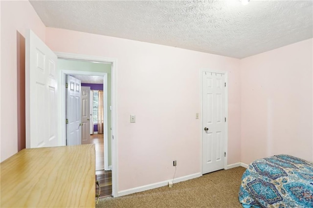 carpeted bedroom with a textured ceiling and baseboards