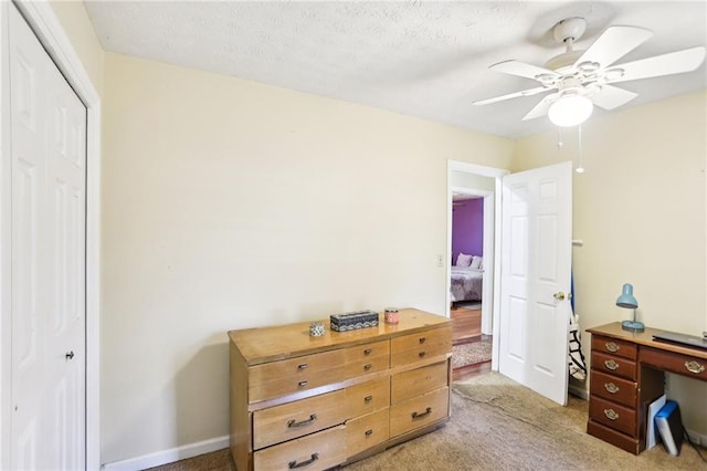 bedroom featuring a ceiling fan, a closet, light carpet, and baseboards