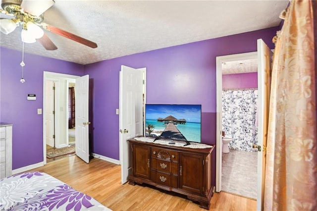 bedroom with baseboards, a ceiling fan, ensuite bath, a textured ceiling, and light wood-type flooring