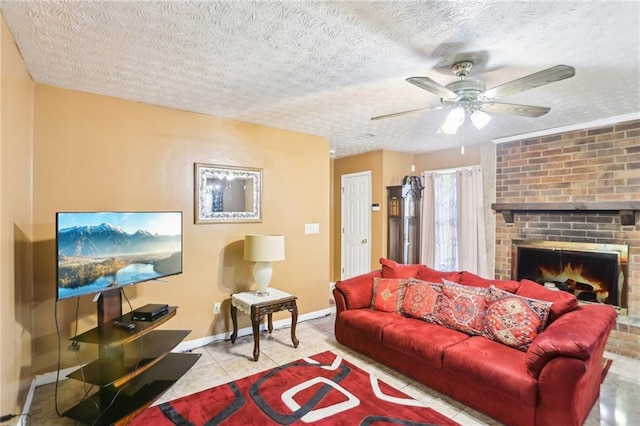 living room featuring a textured ceiling, a ceiling fan, baseboards, a brick fireplace, and tile patterned floors