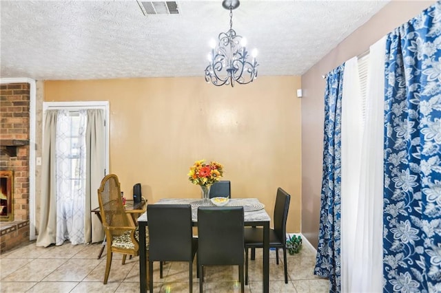 dining space featuring light tile patterned floors, visible vents, an inviting chandelier, a textured ceiling, and a fireplace