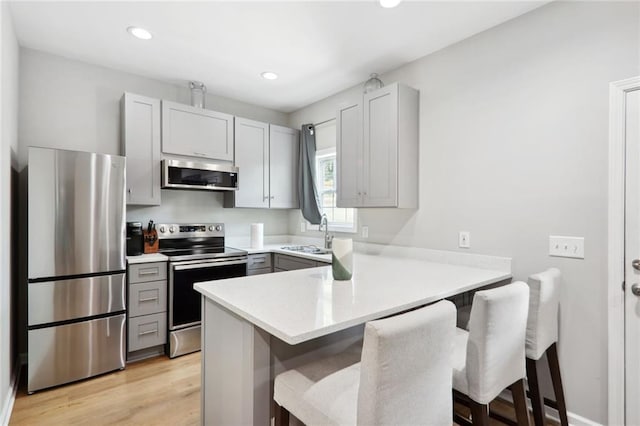 97 Griffin St NW, Atlanta, GA 30314 - kitchen featuring stainless steel appliances, gray cabinetry, a peninsula, a kitchen bar, and light countertops