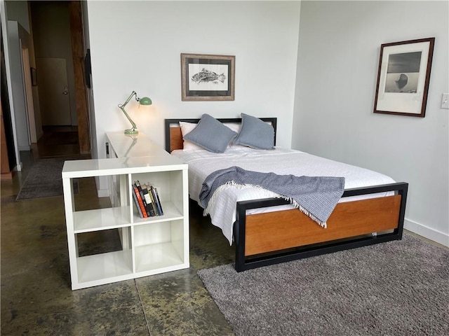 bedroom featuring baseboards and finished concrete floors