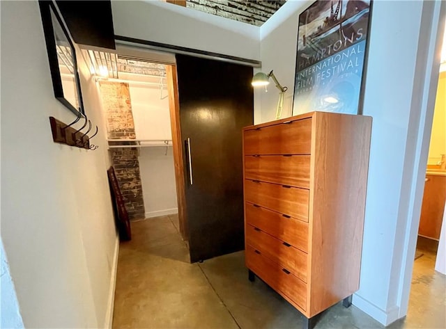 hall featuring baseboards and finished concrete floors