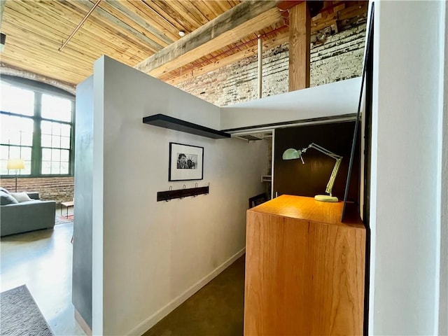 hall featuring baseboards, concrete floors, and wood ceiling