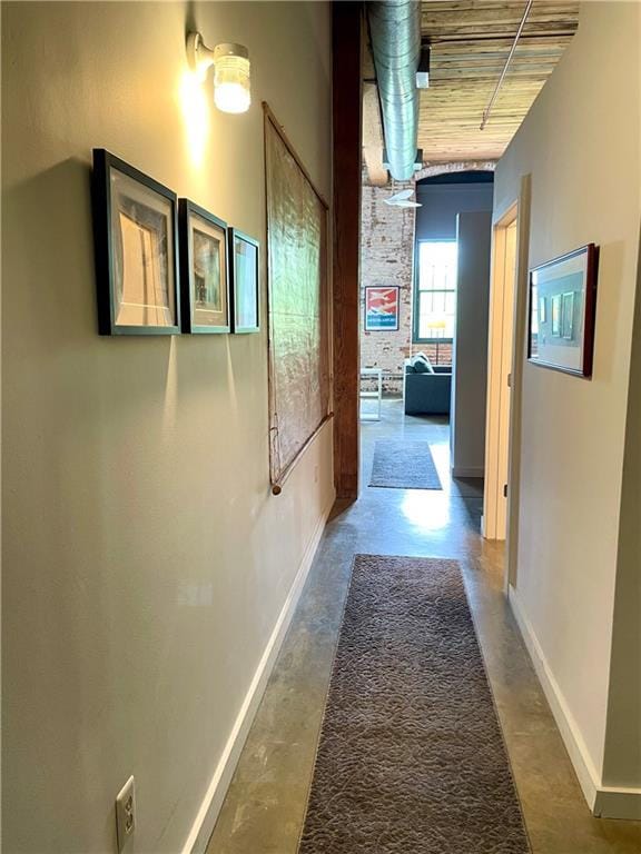 hallway featuring baseboards and concrete floors
