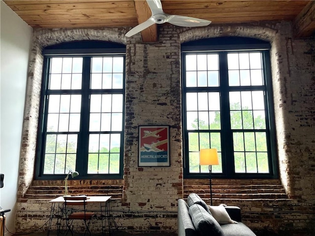 interior space featuring plenty of natural light, wood ceiling, ceiling fan, and brick wall